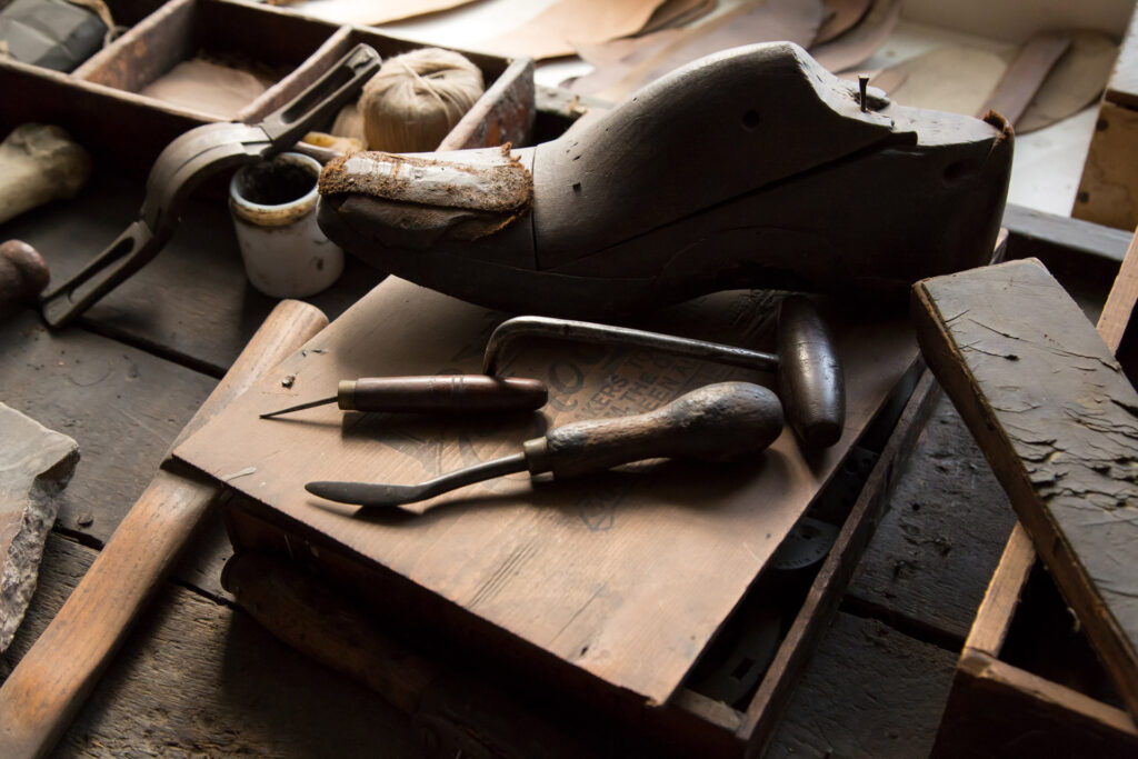A foot shaped last and wooden shoemaking tools on top of a workshop bench