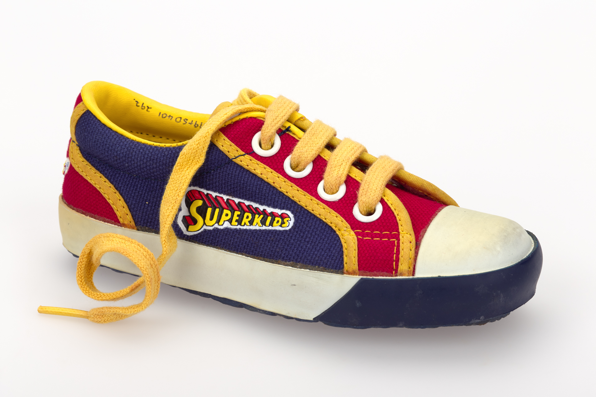 Single right children's navy and red canvas textile front lace shoe with yellow textile binding and white rubber toe cap; Clarks Superkids '82 'Superkid', 1982.